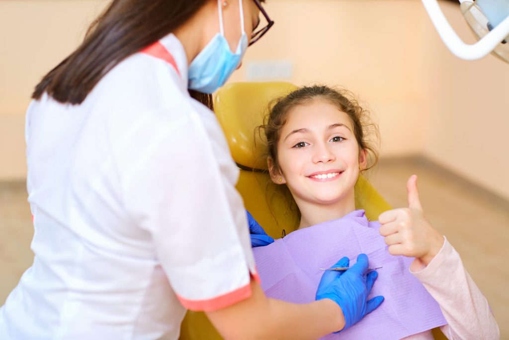 A little girl gives a thumbs up sign before a Pediatric Dentist in Raleigh checks her teeth