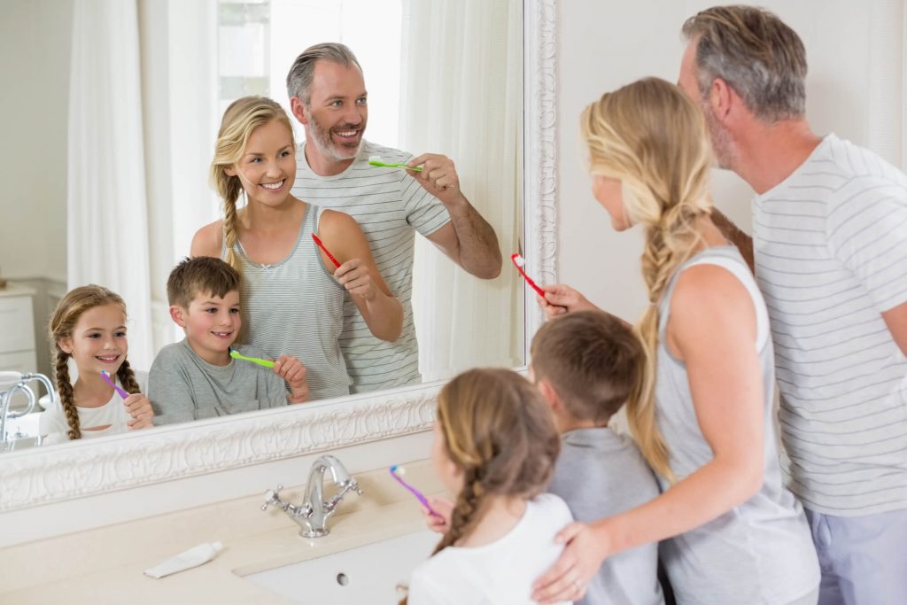 family brushing their teeth after a visit from pediatric dentist Zebulon