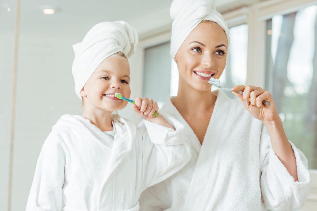 mother and child brushing teeth before going to the the pediatric dentist Zebulon