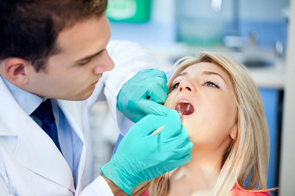 dentist examines patient's mouth before putting composite fillings Raleigh