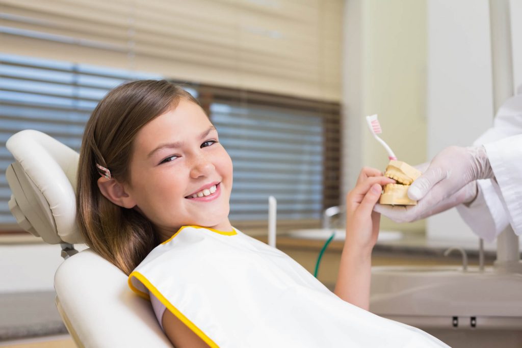 pediatric dentist in Raleigh teaching a girl about oral hygiene