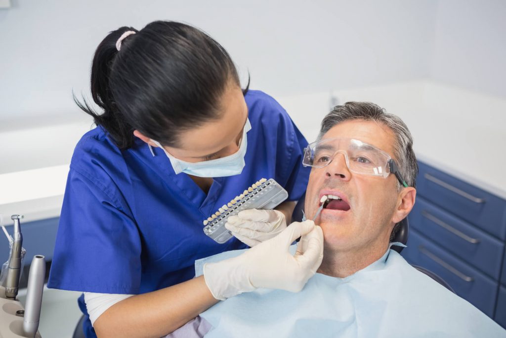 cosmetic dentist in Raleigh choosing a shade for patient's veneers